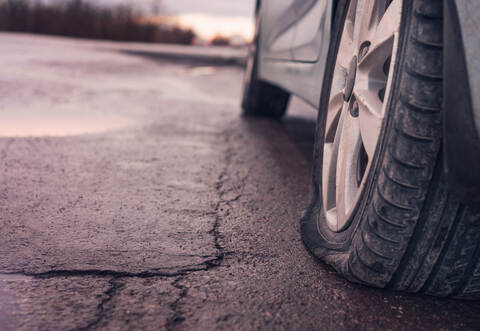 Flat tyre on road. Car tire leak because of nail pounding. Toned