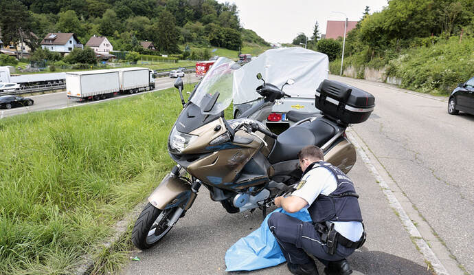 Ein Polizist untersucht nach dem Unfall die Beschädigungen am Motorrad. Ein Polizist untersucht nach dem Unfall die Beschädigungen am Motorrad.