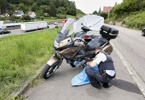 Ein Polizist untersucht nach dem Unfall die Beschädigungen am Motorrad.