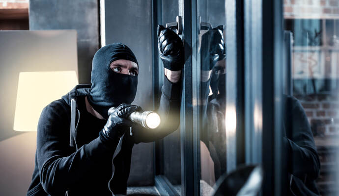 Masked burglar breaking into the house