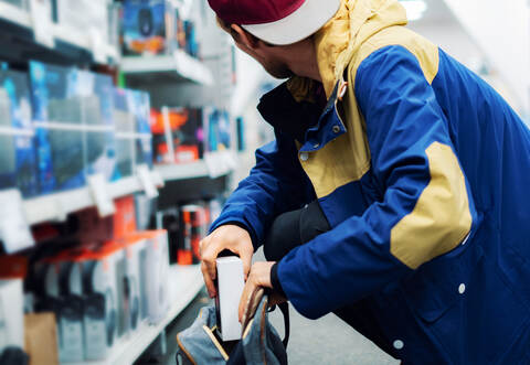 close up the  consumer  thief’s hands putting the new gadget in the pocket in the store 