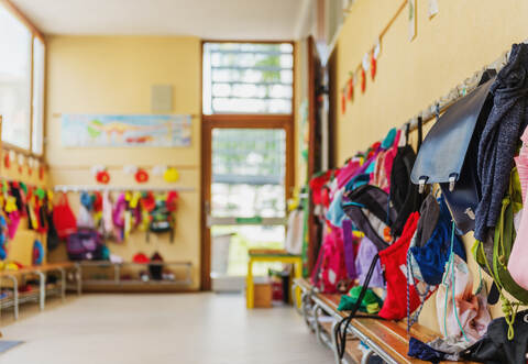 Empty hallway in the school, backpacks and bags on hooks, bright recreation room