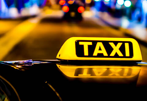 Night photo of a taxi car. Taxi sign on the car roof glowing in the dark