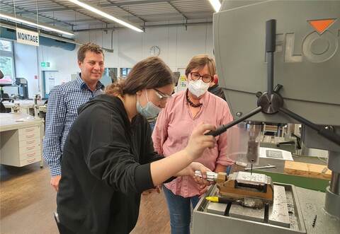 Konzentriert ist Schülerin Ecem bei der Sache. Michael Volpp, BFW-Teamleiter Fertigung, und Uta Schulte, Bildungsbegleiterinnen des Internationalen Bundes, schauen ihr interessiert über die Schulter.