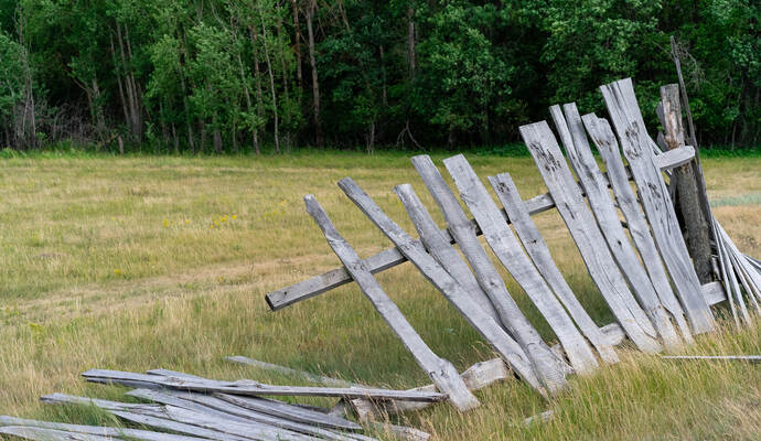 old wooden rickety fence. Abandoned field with an old wooden fence. Old broken wooden fence. Summer sunny day with blue sky and 