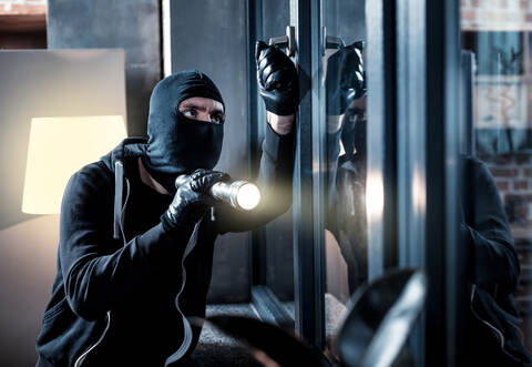 Masked burglar breaking into the house