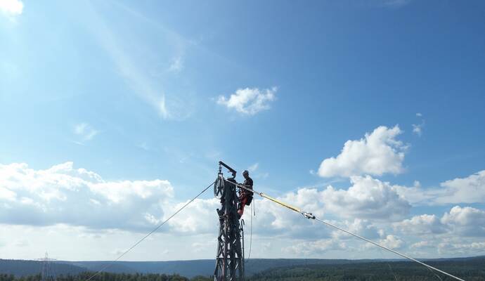 In schwindelerregender Höhe führen die Arbeiter Seilzugarbeiten an der 1443 Meter langen Freileitung durch.