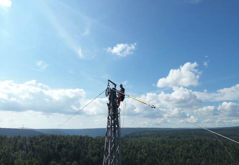 In schwindelerregender Höhe führen die Arbeiter Seilzugarbeiten an der 1443 Meter langen Freileitung durch.