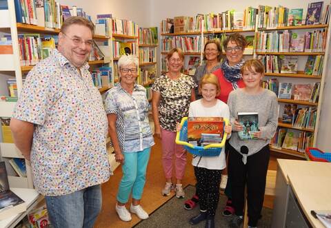 Erstrahlt in neuem Glanz: Zusammen mit den übrigen Ehrenamtlichen und einer Familie, die oft zum Ausleihen vorbeikommt, freut sich Peter Asmuth (links) über den neu gestalteten Eingangsbereich.   Roller