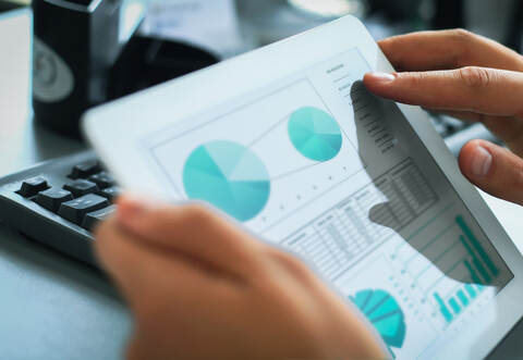 Business person analyzing financial statistics displayed on the tablet screen