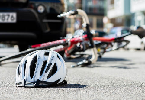 Close-up of a bicycling helmet on the asphalt  next to a bicycle