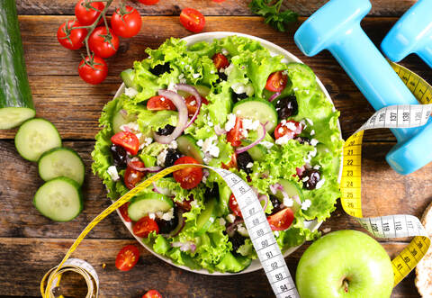 diet food concept- salad with dumbbell and meter