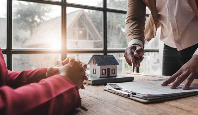 House model with agent and customer discussing for contract to buy, get insurance or loan real estate or property..