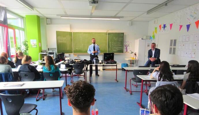 Unterricht der besonderen Art: Polizeioberkommissar Fabian Faigle erklärt den Realschülern in Königsbach Grundsätze des rechtsstaatlichen Handelns der Polizei. Rechts hinten im Bild: Amtsgerichtdirektor Oliver Weik, der den zweiten Teil des Projekttags übernahm.