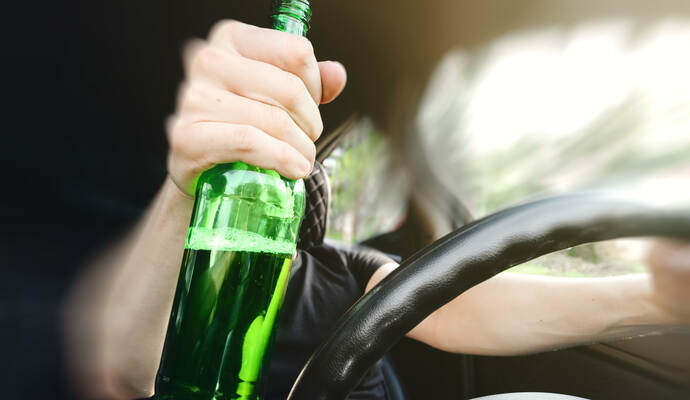 Die Polizei stoppt nach einem Hinweis eine Alkoholfahrt in Mühlacker. Close-up of a bottle of Alcohol in the driver hand at the wheel of car. Alcohol driving concept