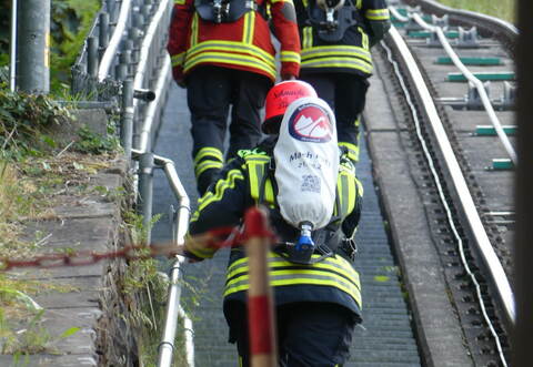 In voller Schutzausrüstung und mit Atemluftflaschen unterwegs auf den „Stäffele“ zum Sommerberg: einige der insgesamt 51 Feuerwehrangehörigen