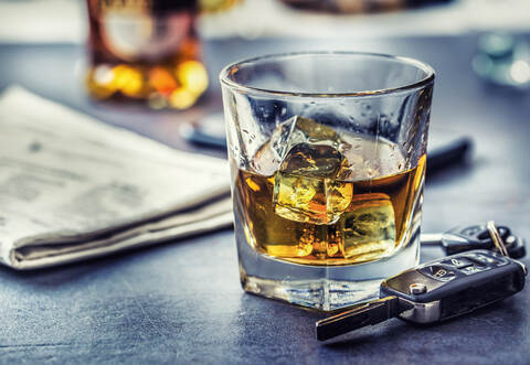 Car keys and glass of alcohol on table in pub or restaurant.
