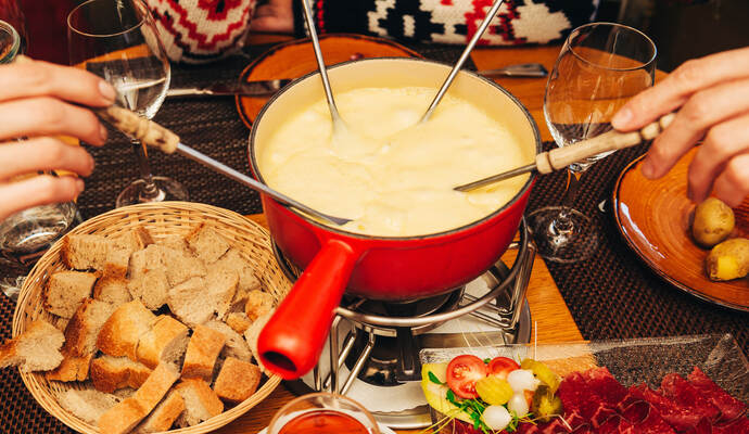 Friends eating cheese fondue in a cozy traditional swiss restaurant 