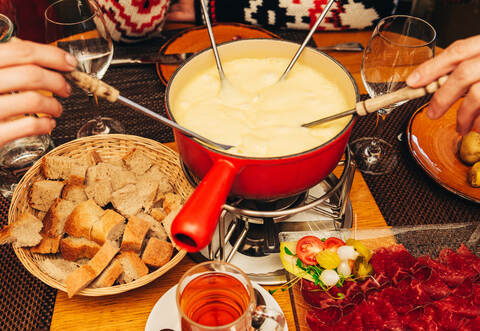 Friends eating cheese fondue in a cozy traditional swiss restaurant 