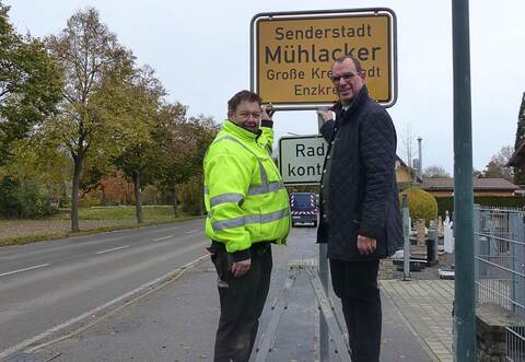 OB Frank Schneider (rechts) und Armin Saussele vom Bauhof bei der Einweihung des Schildes an der Ortseinfahrt in der Lomersheimer Straße.