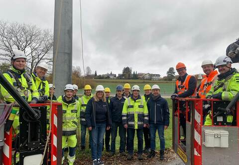 Mit einer Hebebühne hochgefahren und nun wieder auf festem Grund: Mit jeweils einem Helfer stehen Netze BW-Geschäftsführer Christoph Müller (rechts) und Weil der Stadts Bürgermeister Christian Walter mit dem Hauptamtsleiter von Tiefenbronn Manuel Rausch (links) und dem restlichen Team vor dem jetzt unnützen Strommast.