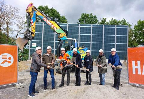 Los geht‘s mit dem Bau der beiden Wohnkomplexe: Arno Linder, Geschäftsführer der Gesellschaft für kommunale Baulanderschließung (GkB, von links), Helmut Schneider, Fraktionsvorsitzender der Freien Wählervereinigung im Gemeinderat, Rudolf H arsch, Geschäftsführer der investierenden Baufirma Harsch, Bürgermeister Norman Tank, Bauleiterin Nathalie Dittrich, Bauplane r Sven Buttenhausen und Björn Dost, Fraktionsvorsitzender der Fraktion Aktive Bürger, greifen symbolisch zum Spaten. Im Hintergrund: die über neun Meter hohe Lärmschutzwand, um die es im Vorfeld viel Furore gab.