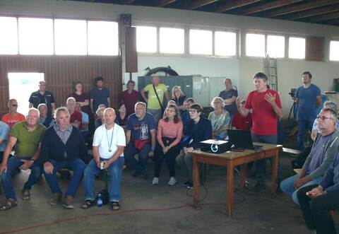 35 Mitglieder der Obstbaugenossenschaft Bauschlott treffen sich in der Obsthalle zu einer Versammlung wegen der geplanten Stromproduktion durch Agri-Photovoltaik. Hansjörg Vollmer (stehend) und Hermann Meschenmoser (vorne links sitzend) informieren.