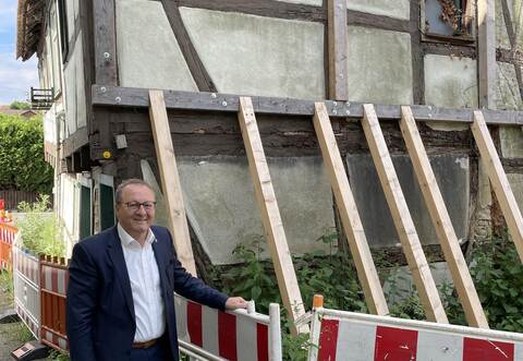 Bürgermeister Thomas Nowitzki zeigt die maroden Fachwerkbalken, die abgestützt werden müssen, damit sich das Haus nicht noch weiter neigt.