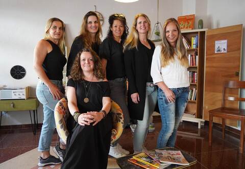 Janine Schütz (sitzend) und Gaschu Bieber, Ines Magas, Nina Ebker, Katja Diesner und Sonja Buscher (von links) stehen im Wohnzimmer des Mitmach-Ateliers in der Hausnummer 23.