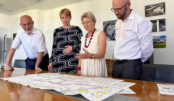 Wolf Ehrenberg (CEO der Neumo in Knittlingen, von links), Staatssekretärin Andrea Lindlohr (Grüne), Enzkreis-Landtagsabgeordnete Stefanie Seemann (Grüne) und Knittlingens Bürgermeister Alexander Kozel informieren sich über den Bebauungsplan des neuen Wohnquartiers.