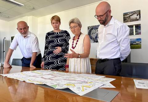 Wolf Ehrenberg (CEO der Neumo in Knittlingen, von links), Staatssekretärin Andrea Lindlohr (Grüne), Enzkreis-Landtagsabgeordnete Stefanie Seemann (Grüne) und Knittlingens Bürgermeister Alexander Kozel informieren sich über den Bebauungsplan des neuen Wohnquartiers.
